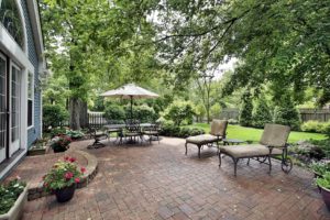 Paver patio in backyard with covered dining table and seating